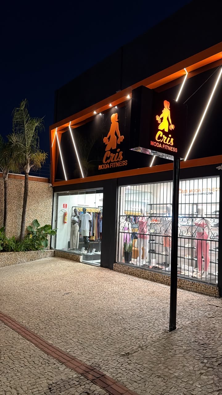 Fachada iluminada da loja Cris Moda Fitness à noite